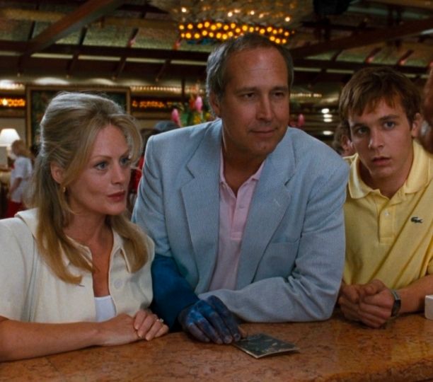 Clark, Ellen, and Rusty Griswold standing at a hotel check in desk